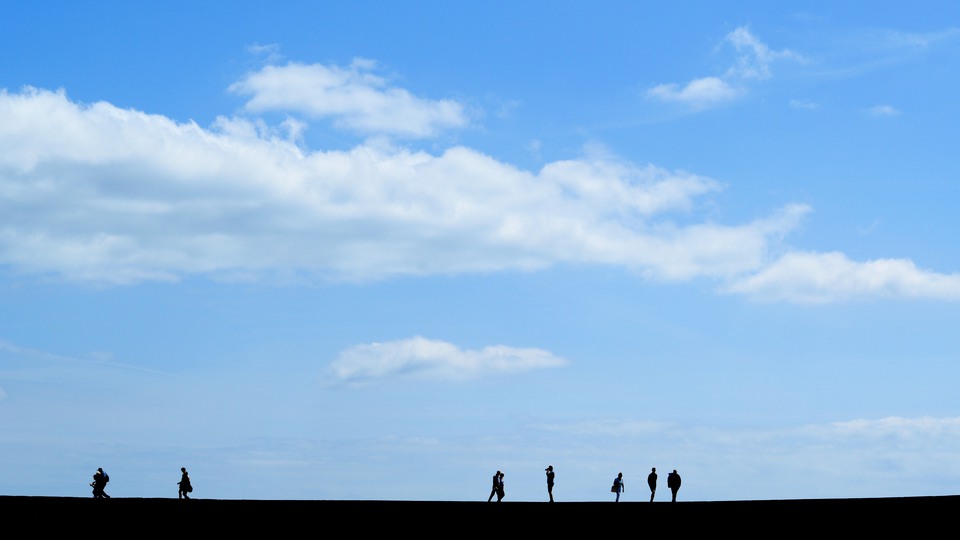 Silhouette of people walk on The Cobb  in Lyme Regis, Dorset